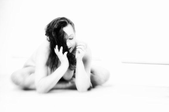 Frau in künstlerischer Pose mit langem Haar, in schwarz-weiß gekleidet.