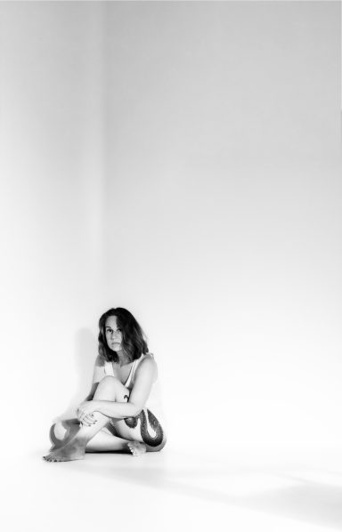 Junge Frau sitzt in einer Ecke, umgeben von leeren weißen Wänden.